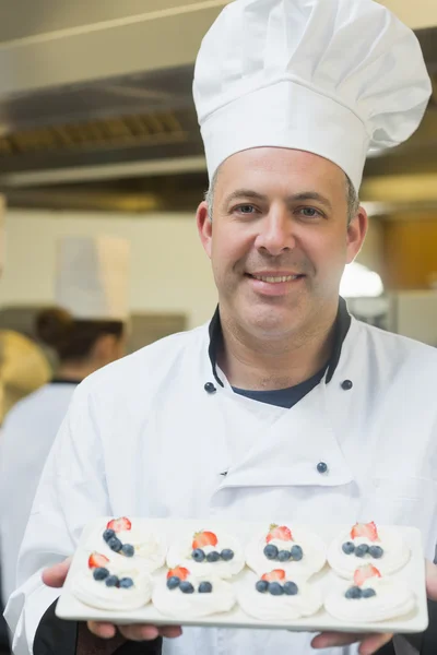 Gelukkig chef-kok presenteert plaat van schuimgebakjes — Stockfoto