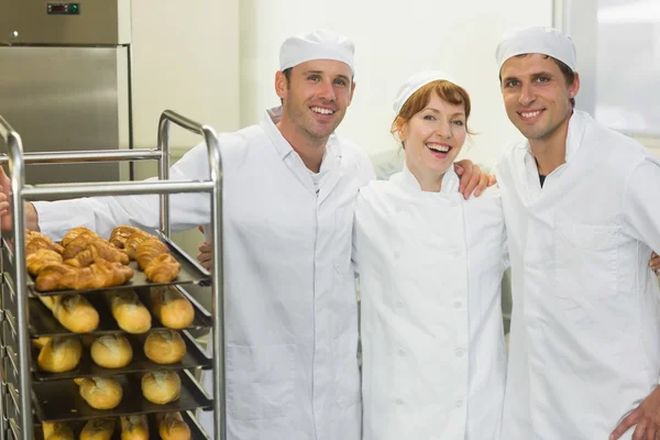 Tres jóvenes panaderos posando juntos en una panadería —  Fotos de Stock