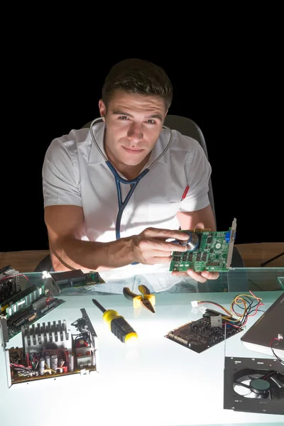 Lachende computer ingenieur behandeling van hardware met stethoscoop per nacht — Stockfoto