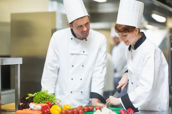 Vrouwelijke chef-kok snijden van groenten met collega — Stockfoto