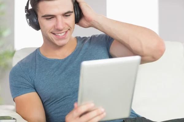Hombre guapo feliz usando tableta escuchando música — Foto de Stock