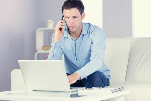 Beau homme décontracté utilisant ordinateur portable et téléphone — Photo