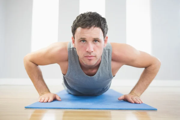 Pohledný sportovní muž dělá push up na modrá mat — Stock fotografie