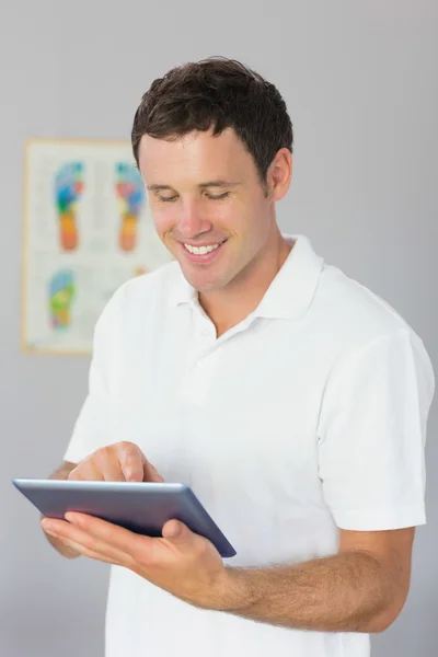 Handsome smiling physiotherapist using tablet — Stock Photo, Image