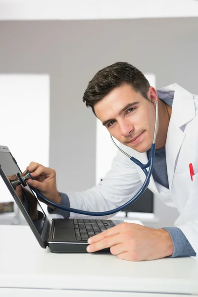 Ingénieur informatique de contenu attrayant examinant l'ordinateur portable avec stéthoscope — Photo