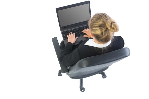 Vista trasera de la mujer de negocios rubia sentada en silla giratoria utilizando el ordenador portátil — Foto de Stock
