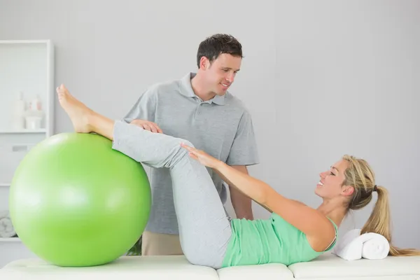 Paciente sosteniendo pelota de ejercicio con piernas —  Fotos de Stock