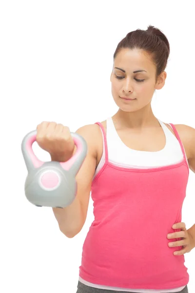 Zufriedene sportliche Brünette mit grauer und pinkfarbener Kettlebell — Stockfoto