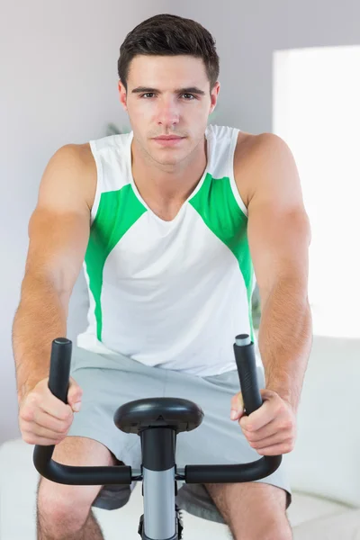 Strenger gutaussehender Mann trainiert auf Heimtrainer — Stockfoto