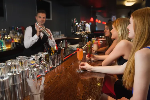 Handsome bartender making cocktails for attractive women — Stock Photo, Image