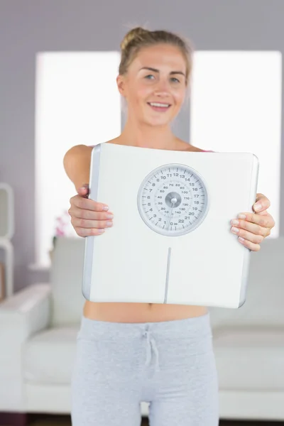 Sporty cheerful blonde holding scales — Stock Photo, Image