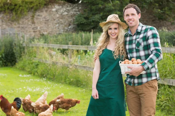Junges Paar posiert auf einer Wiese mit einem Korb voller Eier — Stockfoto