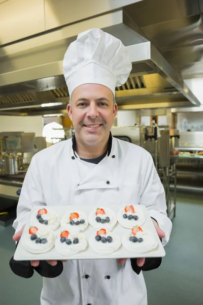 Volwassen chef-kok presenteert met trots plaat van schuimgebakjes — Stockfoto