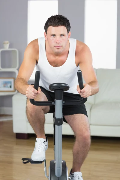 Handsome sporty man exercising on bike looking at camera — Stock Photo, Image