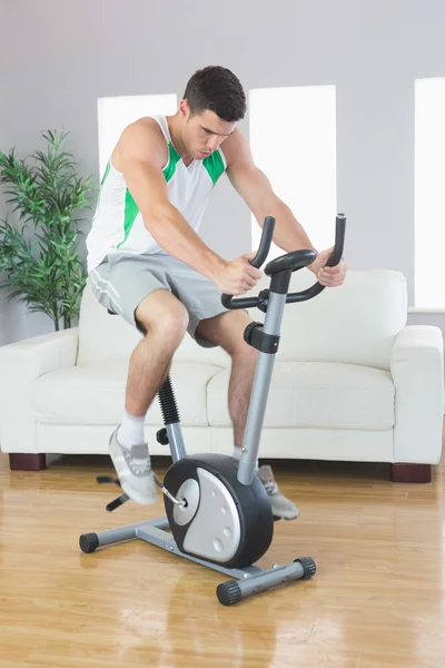 Esportivo bonito homem formação em bicicleta de exercício — Fotografia de Stock