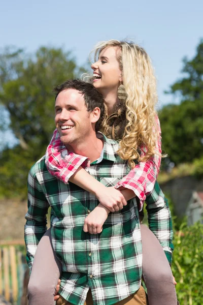 Człowiek daje jego piękna dziewczyna piggyback jazdy — Zdjęcie stockowe