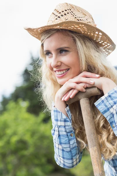 Mooie blonde vrouw leunend op een schop — Stockfoto