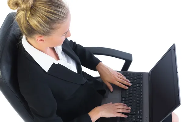 Сосредоточенная молодая деловая женщина, работающая со своей записной книжкой, сидя на офисном стуле — стоковое фото
