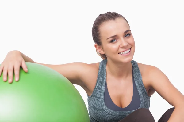 Sorrindo mulher desportiva sentada ao lado de uma bola de fitness — Fotografia de Stock