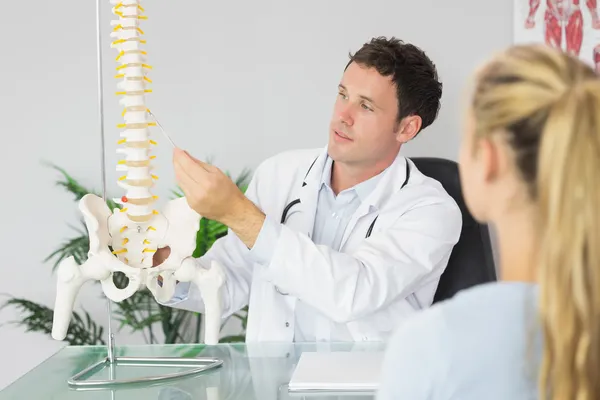 Zufriedener Arzt zeigt einem Patienten etwas am Skelettmodell — Stockfoto