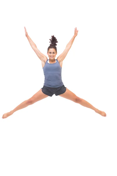 Smiling sporty brunette jumping in the air — Stock Photo, Image