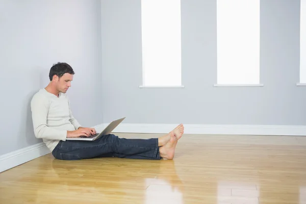 Casual good looking man leaning against wall using laptop — Stock Photo, Image