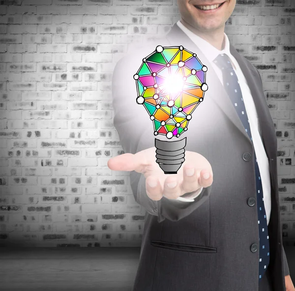 Close up of businessmans hand showing holographic light bulb — Stock Photo, Image