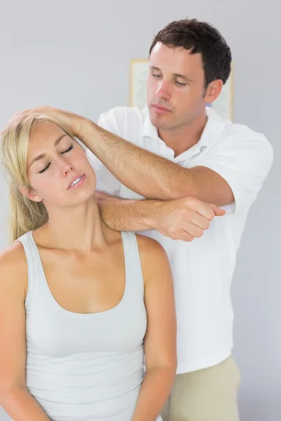 Fisioterapeuta guapo masajeando pacientes cuello con codo — Foto de Stock