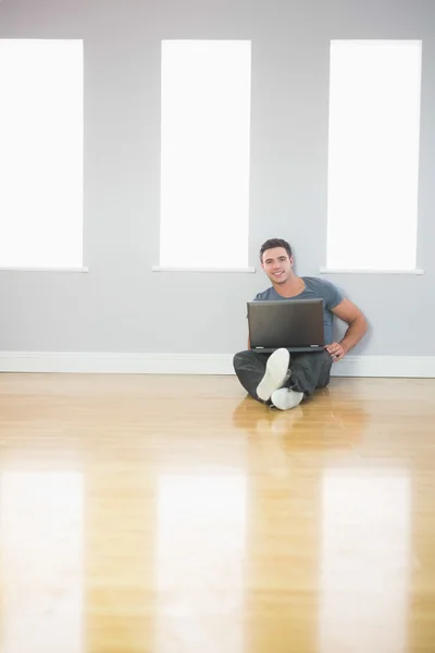 Szczęśliwy, przystojny mężczyzna, pochylony na ścianę za pomocą laptopa — Zdjęcie stockowe