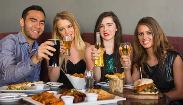 Amigos cenando juntos sonriendo a la cámara — Foto de Stock