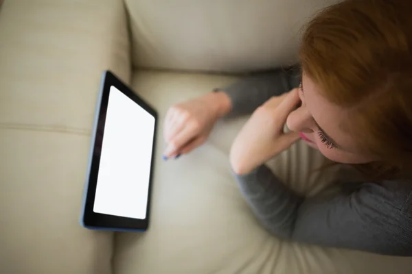 Pelirroja acostada en el sofá viendo su tableta PC — Foto de Stock