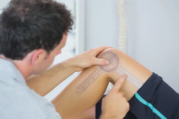 Fysiotherapeut controle knie met goniometer — Stockfoto