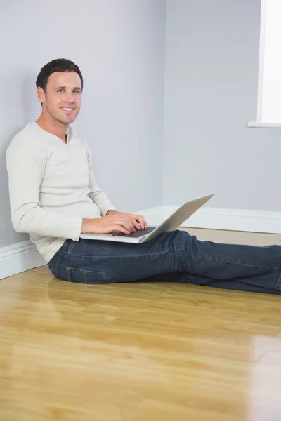 Casual cheerful man leaning against wall using laptop — Stock Photo, Image