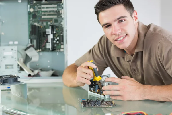 Schöner lächelnder Computeringenieur, der Hardware mit einer Zange repariert — Stockfoto