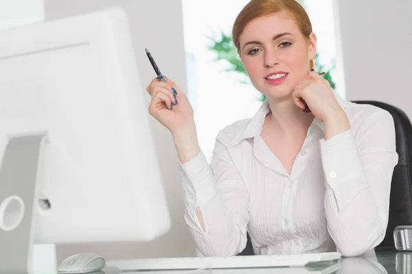 Stern businesswoman working at her desk holding pen — Stock Photo, Image