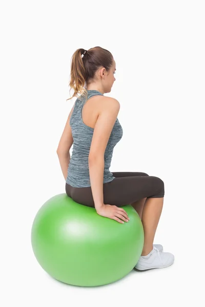 Vue latérale de la femme à queue de cheval assise sur une balle de fitness — Photo