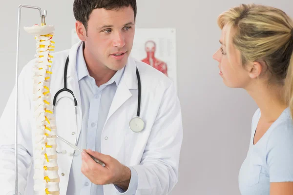 Un médico guapo mostrando a un paciente algo sobre el modelo de esqueleto —  Fotos de Stock