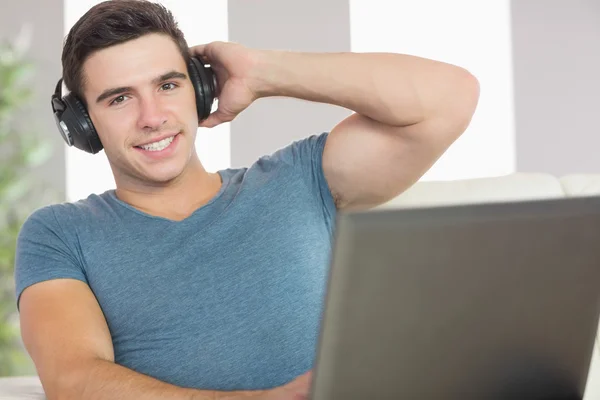 Hombre guapo alegre usando el ordenador portátil escuchando música — Foto de Stock