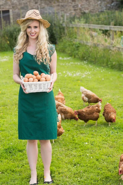 Sorrindo mulher bonita apresentando uma cesta cheia de ovos — Fotografia de Stock