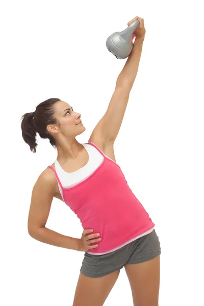 Happy sporty brunette holding grey and kettlebell — Stock Photo, Image