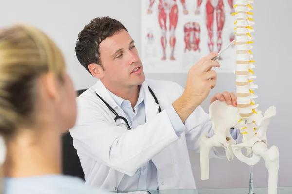 Gut aussehender Arzt zeigt einem Patienten etwas am Skelettmodell — Stockfoto