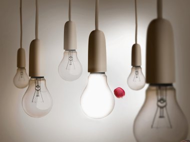 Red apple being thrown between light bulbs clipart