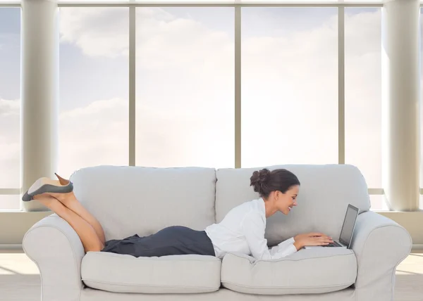 Деловая женщина лежит на диване с помощью ноутбука — стоковое фото