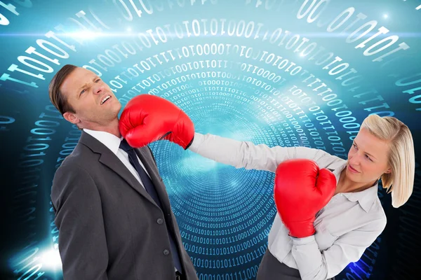 Businesswoman hitting colleague with her boxing gloves — Stock Photo, Image