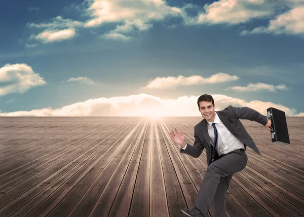 Cheerful man holding a suitcase and running — Stock Photo, Image