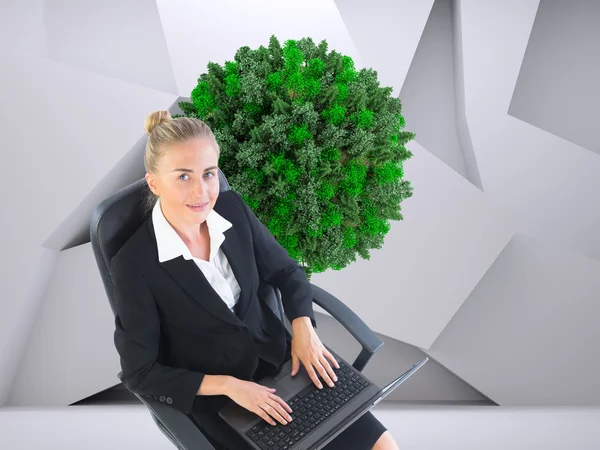 Imagen compuesta de una mujer de negocios sentada en una silla giratoria con portátil — Foto de Stock