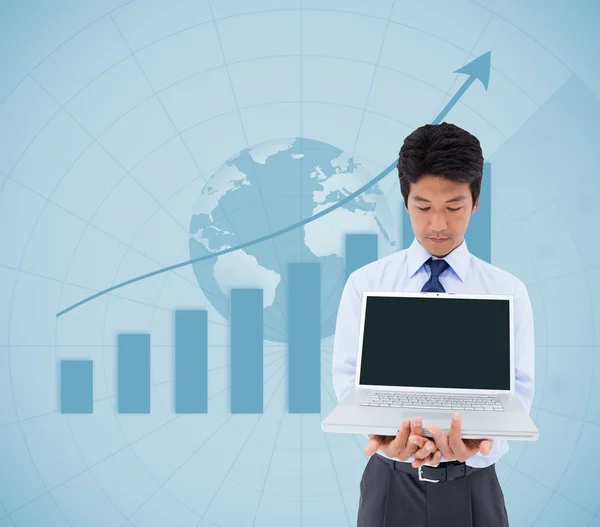 Businessman showing a laptop in front of statistic — Stock Photo, Image