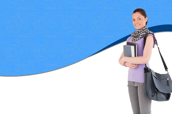Attractive student holding books and her bag while standing — Stock Photo, Image