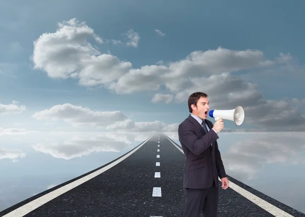 Standing businessman shouting through a megaphone — Stock Photo, Image