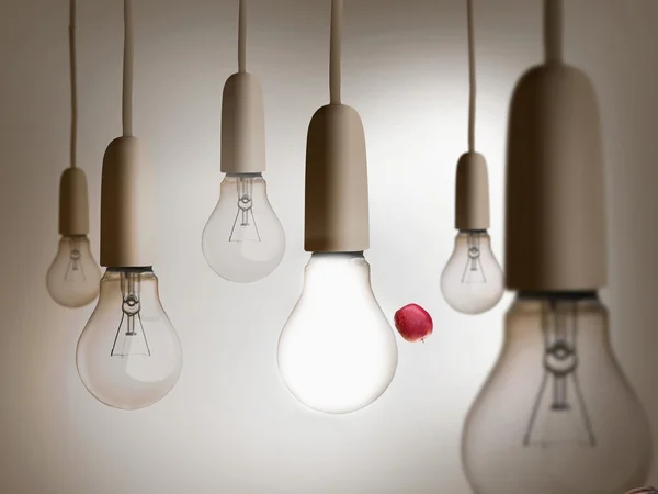 Red apple being thrown between light bulbs — Stock Photo, Image